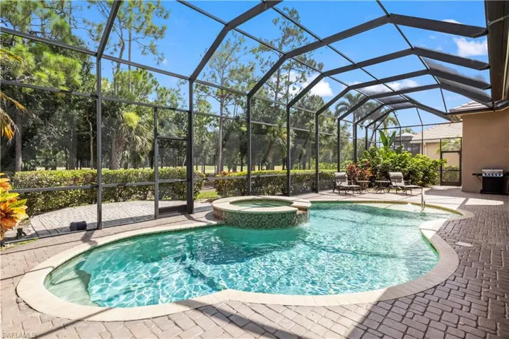 View of swimming pool featuring a patio area, an in ground hot tub, and glass enclosure