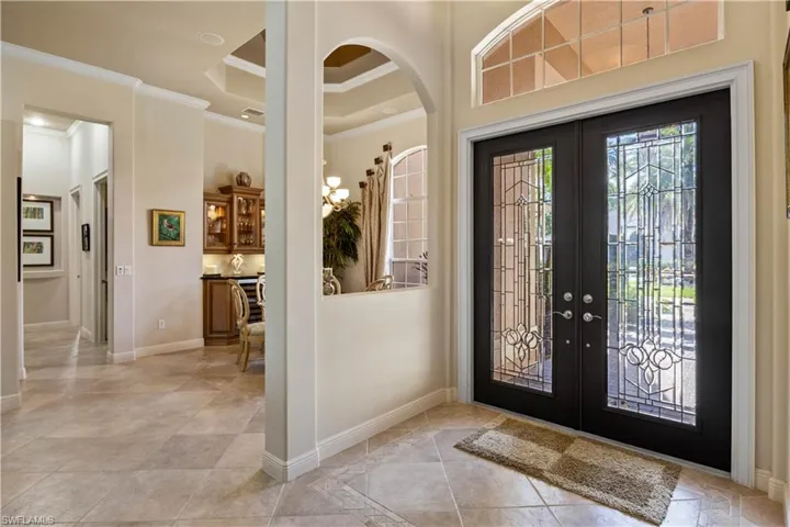 Entrance foyer with light tile patterned flooring, a raised ceiling, french doors, and ornamental molding