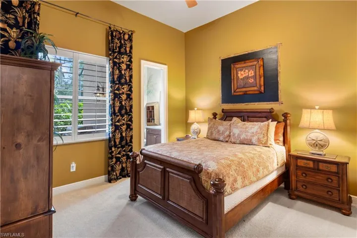 Carpeted bedroom with ceiling fan and connected bathroom