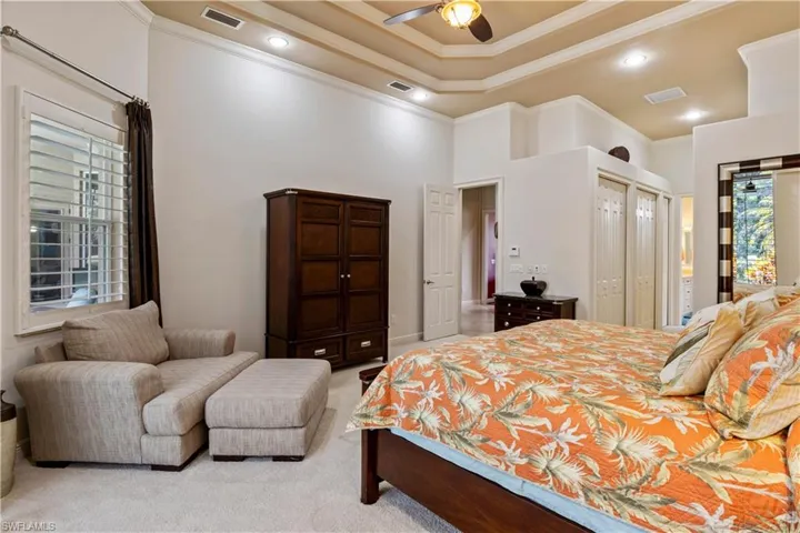 Bedroom featuring light colored carpet, multiple windows, and ceiling fan