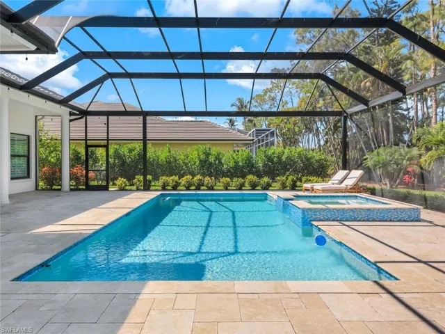 View of swimming pool with a patio area, a pool with connected hot tub, and glass enclosure