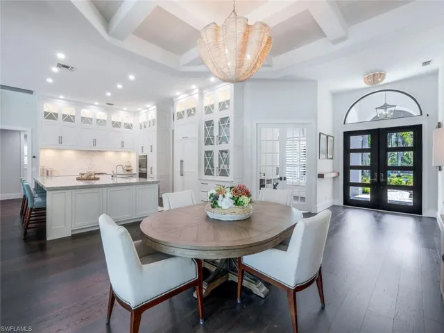 Dining room with dark wood-type flooring, coffered ceiling, visible vents, french doors, and plenty of natural light