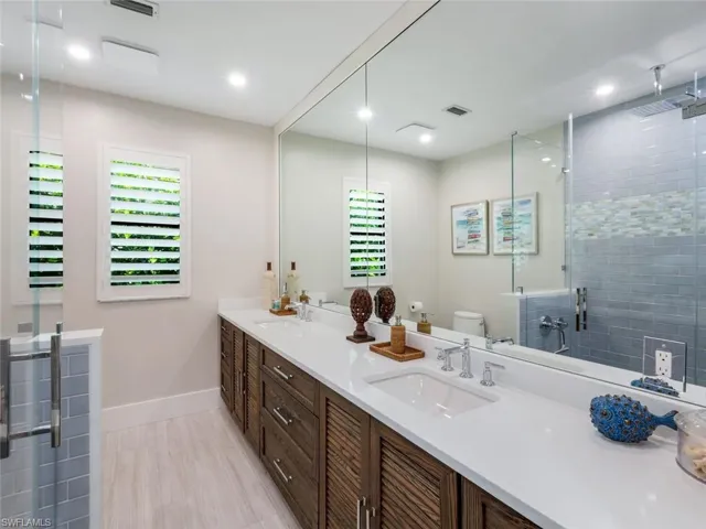 Full bath with toilet, a shower stall, double vanity, and a sink
