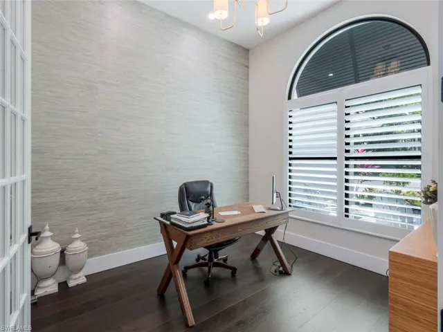 Office area featuring a chandelier, wallpapered walls, dark wood-style flooring, and baseboards