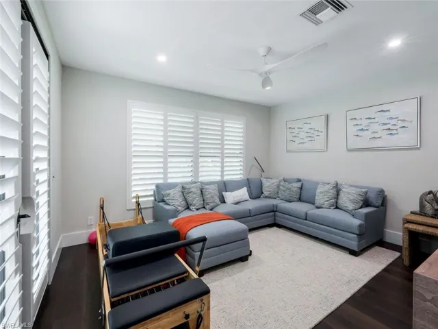 Living room with a ceiling fan, visible vents, dark wood finished floors, and baseboards