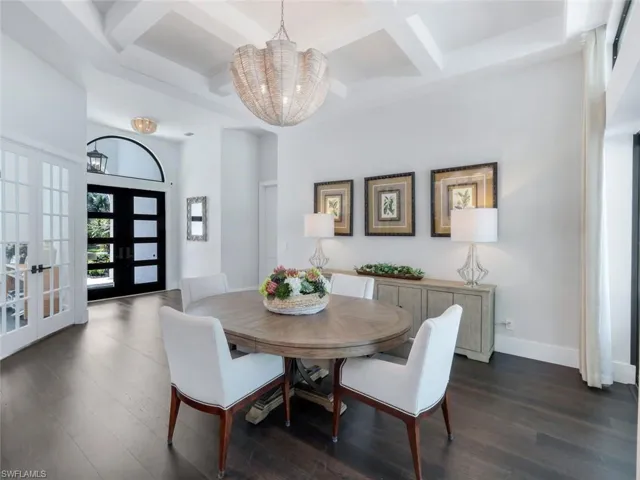 Dining space featuring a chandelier, french doors, dark wood-type flooring, and coffered ceiling