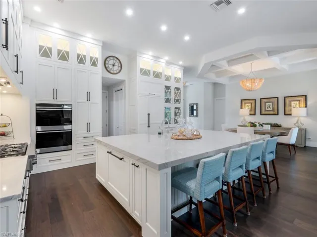 Kitchen featuring visible vents, dark wood finished floors, a large island, multiple ovens, and white cabinetry
