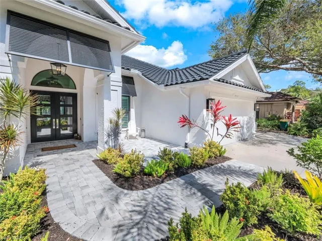 Doorway to property featuring french doors, a tile roof, an attached garage, and stucco siding