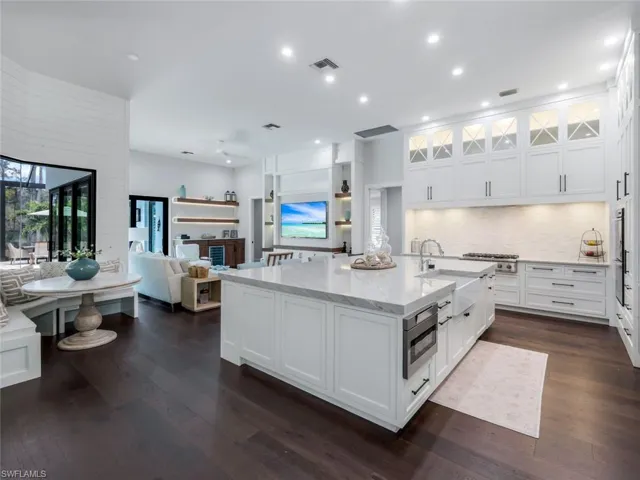 Kitchen with a sink, visible vents, white cabinets, light stone countertops, and dark wood finished floors