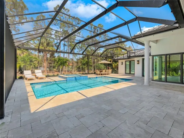 View of pool featuring a pool with connected hot tub, a patio, and a lanai