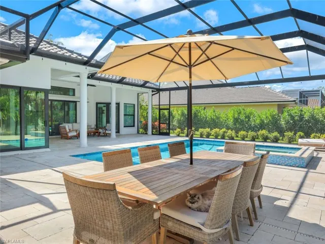View of swimming pool featuring a pool with connected hot tub, outdoor lounge area, outdoor dining space, glass enclosure, and a patio area