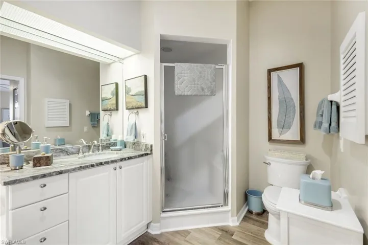 Bathroom with vanity, a shower stall, and light wood-style flooring