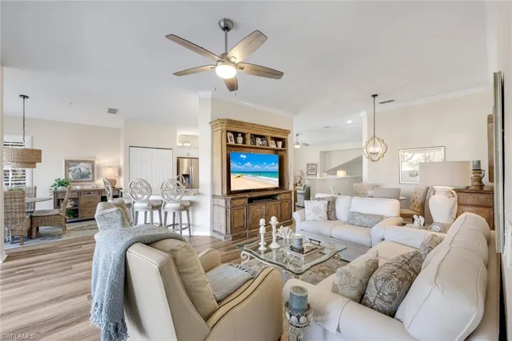 Living area with wood finished floors, ornamental molding, a chandelier, and ceiling fan