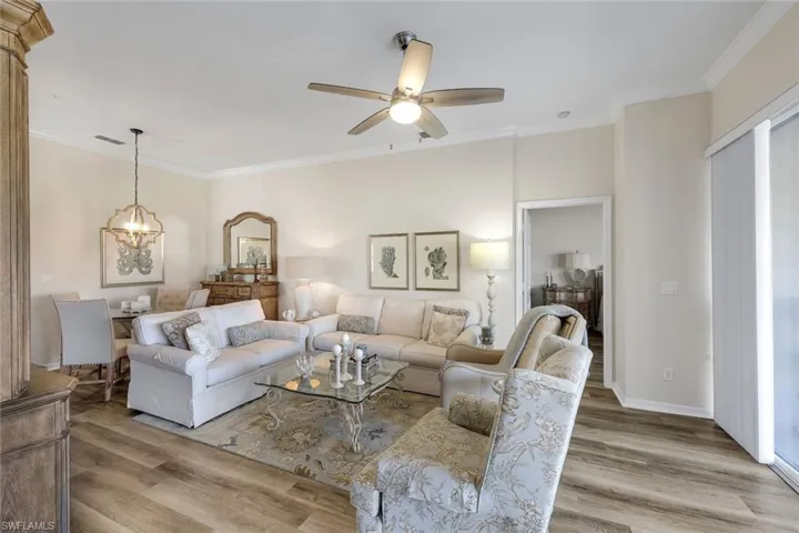 Living area with crown molding, light wood-type flooring, ceiling fan, and hanging lights