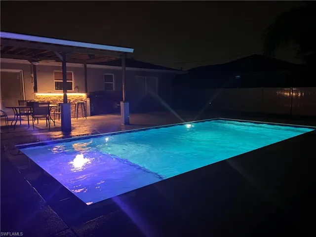 Pool at night featuring a patio area