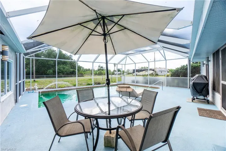 View of patio with area for grilling, a lanai, and a water view