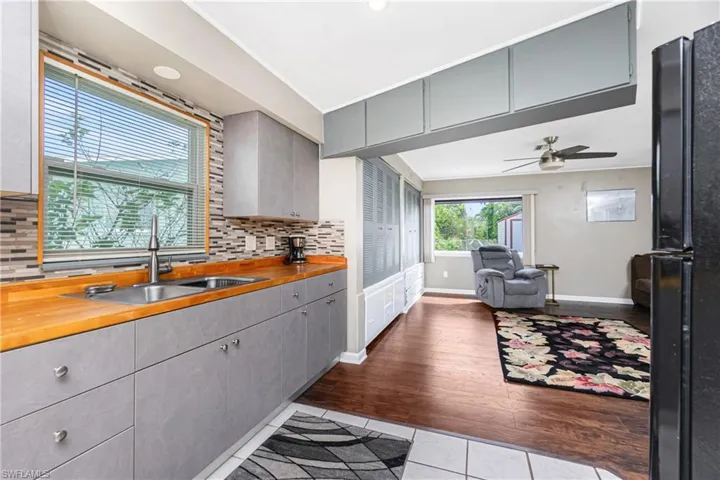 Kitchen with decorative backsplash, sink, light hardwood / wood-style floors, and wooden counters