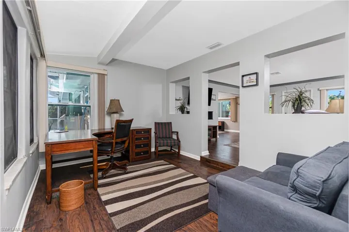 Home office with a wealth of natural light, lofted ceiling with beams, and dark hardwood / wood-style floors