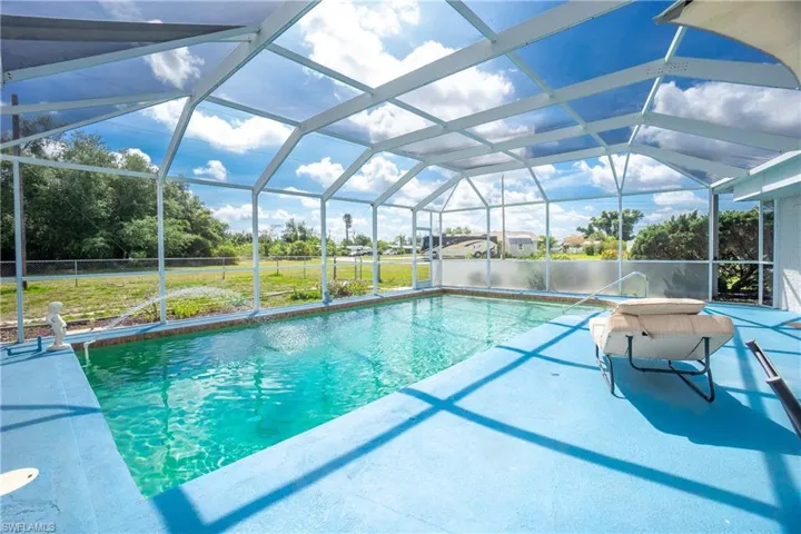 View of pool with a lanai and a lawn