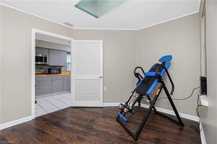 Workout room with wood-type flooring and crown molding