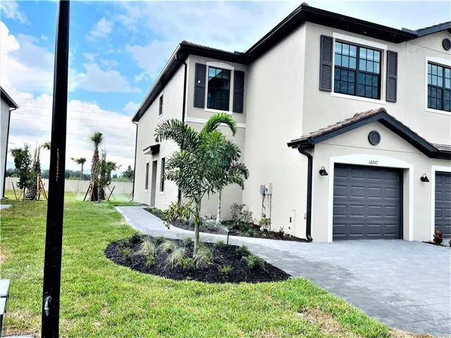 View of front facade with an attached garage, stucco siding, a front lawn, and decorative driveway