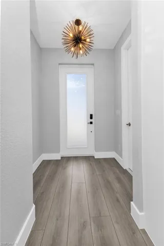 Doorway featuring a chandelier, wood finished floors, and a textured wall