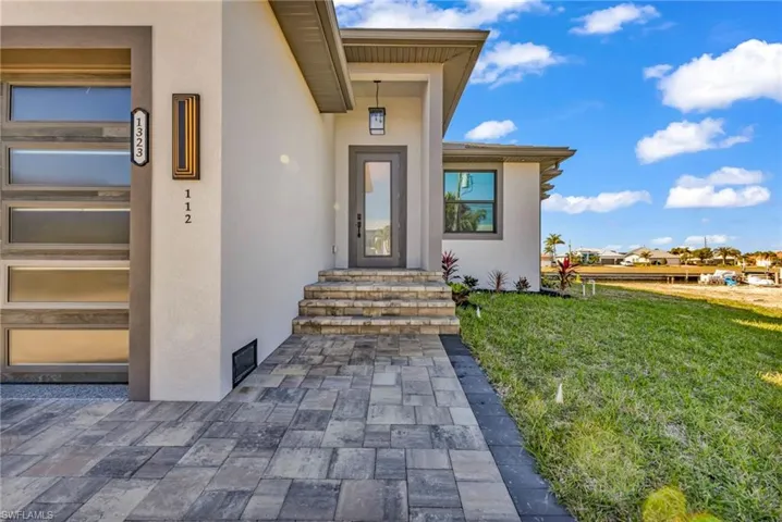Doorway to property with stucco siding and a lawn