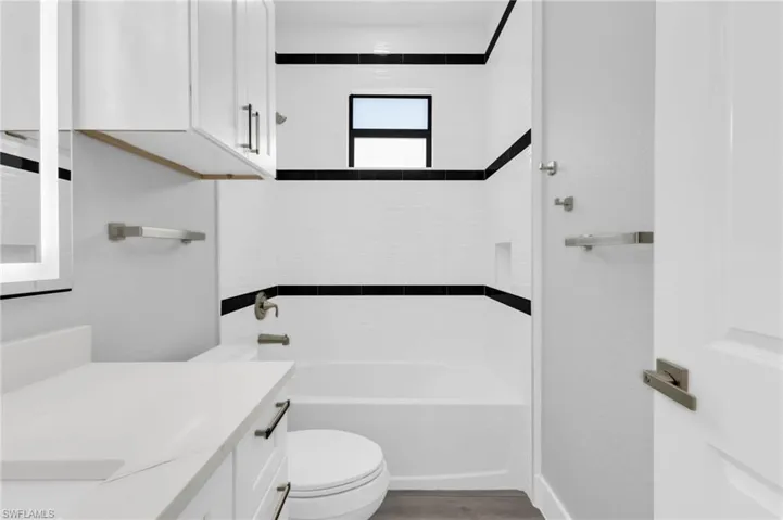 Bathroom featuring vanity, shower / washtub combination, and light wood-style flooring