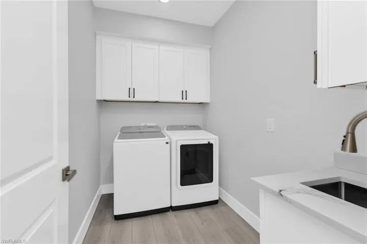 Washroom featuring light wood-style flooring, washing machine and dryer, and cabinet space