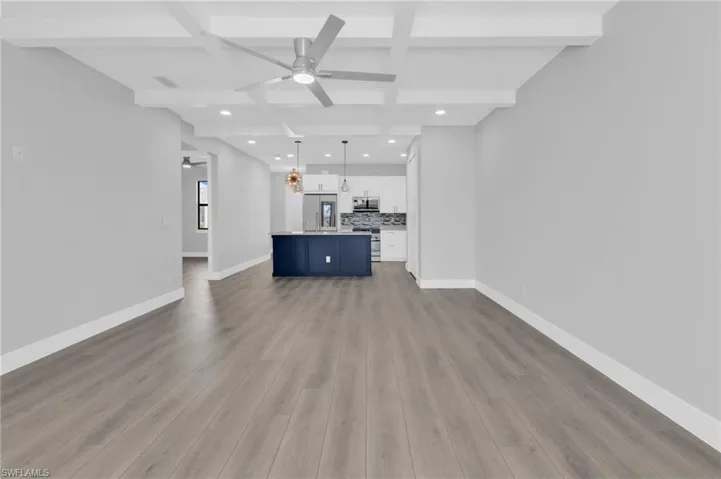 Unfurnished living room with coffered ceiling, beamed ceiling, recessed lighting, a ceiling fan, and dark wood-style floors