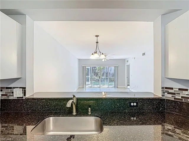 Kitchen featuring visible vents, a sink, dark stone countertops, tasteful backsplash, and white cabinetry