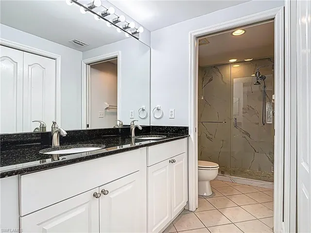 Full bathroom with a sink, a marble finish shower, toilet, and visible vents