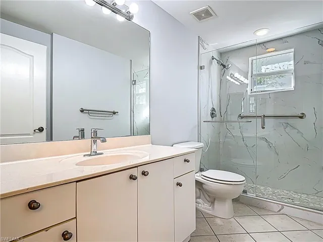Full bathroom with tile patterned floors, visible vents, toilet, a marble finish shower, and vanity