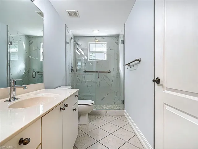 Full bathroom with vanity, toilet, visible vents, and a marble finish shower
