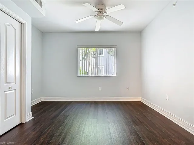 Empty room featuring visible vents, dark wood-style floors, baseboards, and ceiling fan