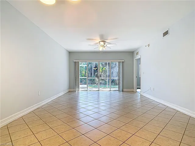 Spare room featuring light tile patterned floors, visible vents, baseboards, and a ceiling fan