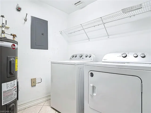Washroom with visible vents, electric water heater, electric panel, laundry area, and washer and dryer