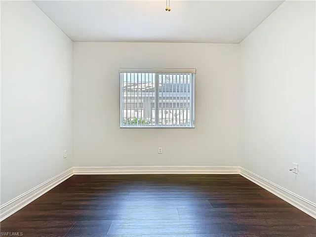 Unfurnished room with dark wood finished floors and baseboards