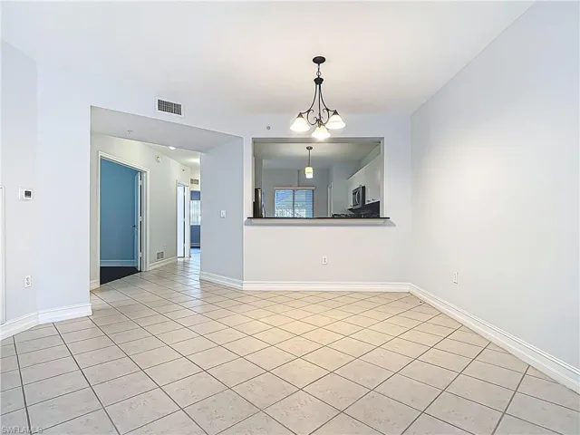 Spare room with light tile patterned flooring, visible vents, and baseboards