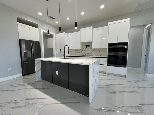Kitchen with sink, white cabinetry, tasteful backsplash, and black refrigerator with ice dispenser