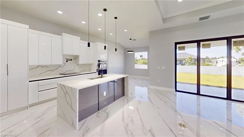 Kitchen featuring light tile patterned flooring, pendant lighting, light stone countertops, and white cabinets