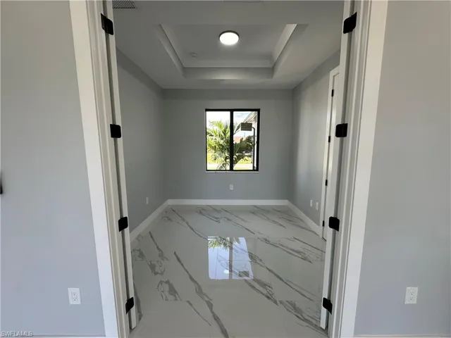 Tiled empty room featuring a tray ceiling