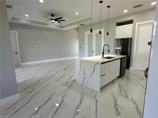 Kitchen featuring white cabinets, light tile patterned flooring, a raised ceiling, and ceiling fan