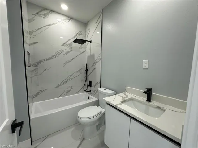 Full bathroom with vanity, tiled shower / bath combo, toilet, and tile patterned flooring