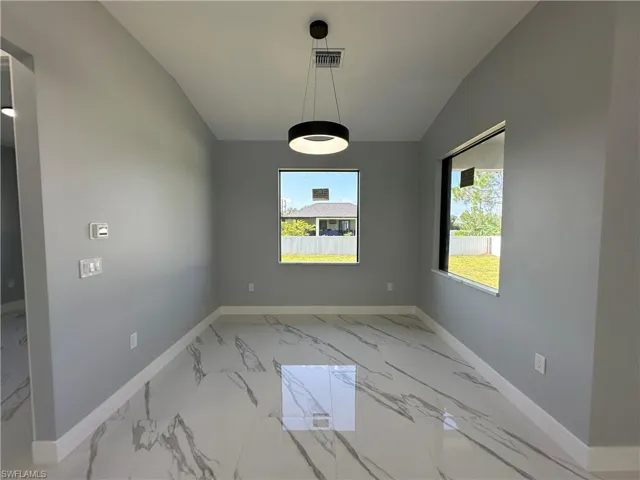 Unfurnished room with light tile patterned floors and vaulted ceiling