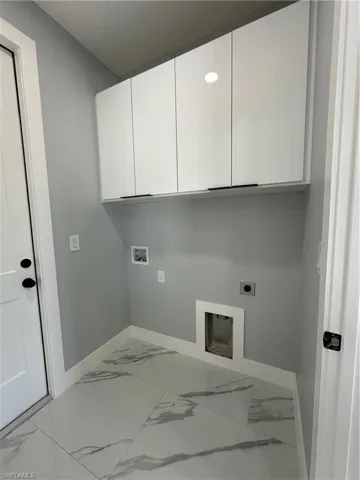 Washroom with electric dryer hookup, cabinets, tile patterned flooring, and washer hookup