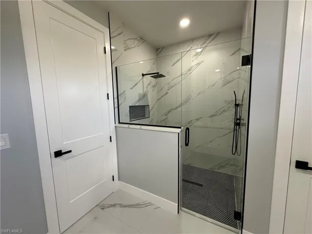 Bathroom with a shower with shower door and tile patterned floors