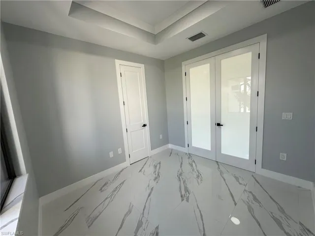 Tiled spare room with french doors and a tray ceiling