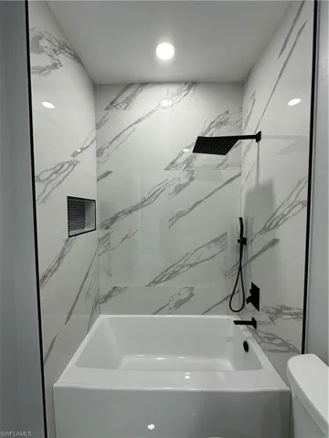 Bathroom featuring tiled shower / bath and toilet