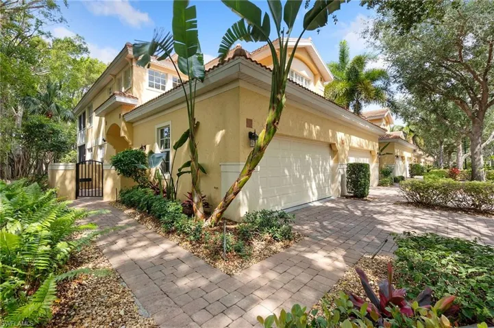 View of side of property featuring a gate, stucco siding, decorative driveway, and a garage